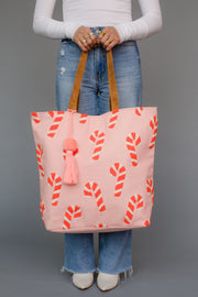 Person holding a pink tote bag with candy cane pattern against a gray background