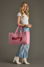 Woman holding a pink tote bag with 'merry' text against a gray background