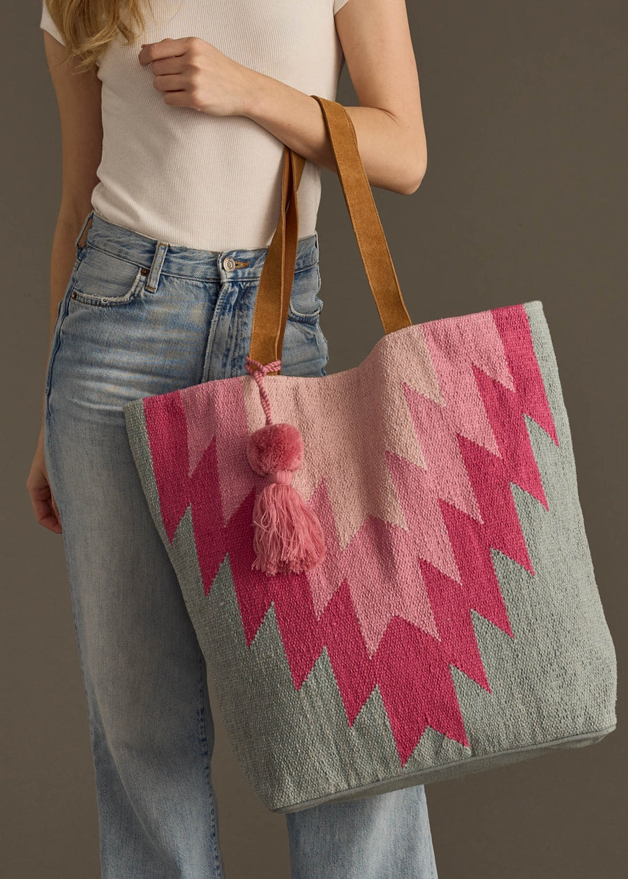 Person holding a colorful tote bag with pink and gray pattern