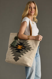 Woman holding a tote bag with a geometric design against a gray background