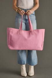 Person holding a pink tote bag against a plain background