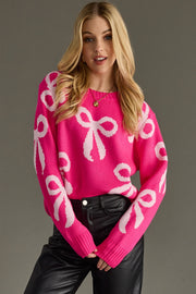 Woman wearing a pink sweater with white bow patterns on a gray background