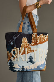 Tote bag with mountain and 'Ski Trip' design held by a person.