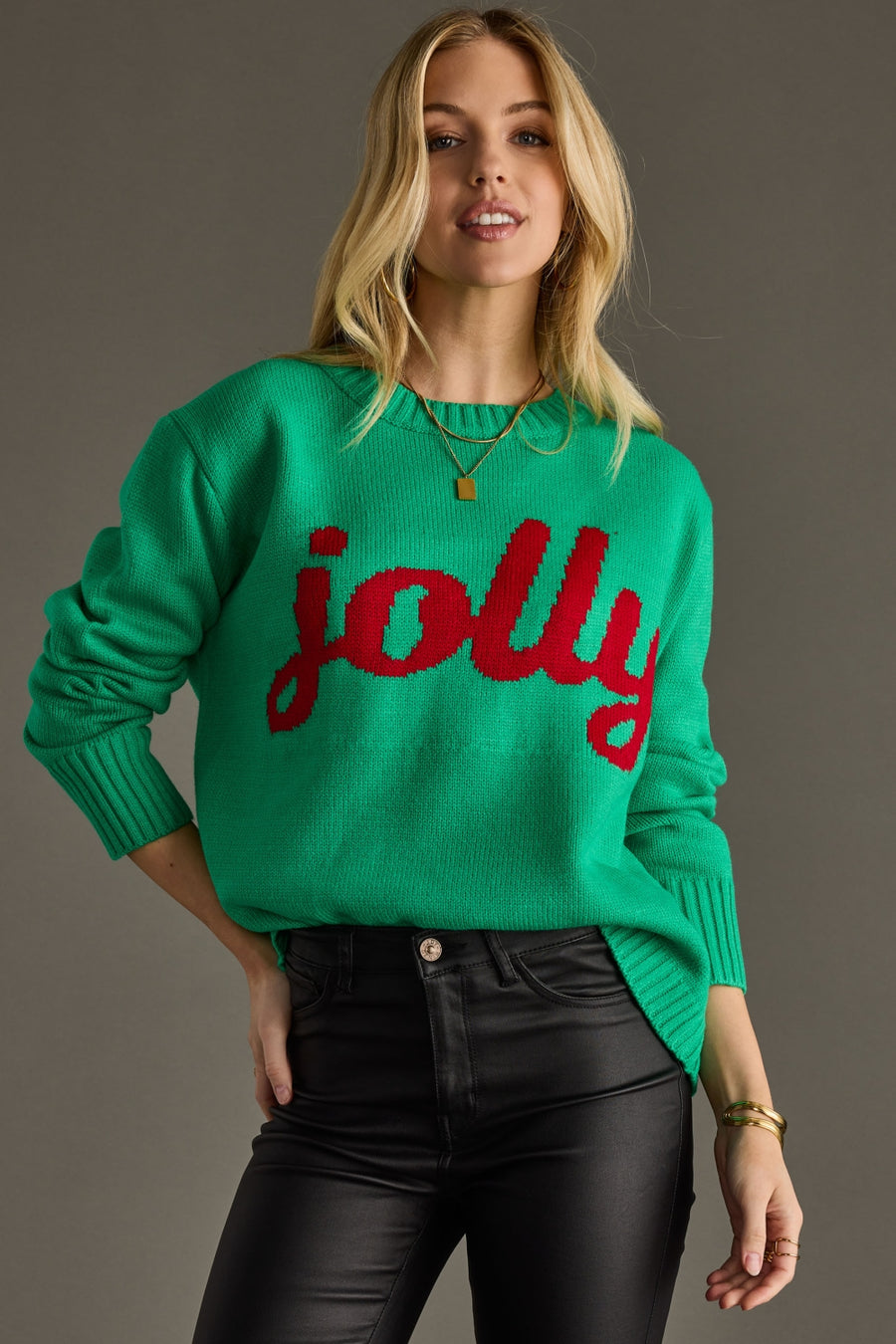 Woman wearing a green sweater with 'jolly' in red text against a gray background