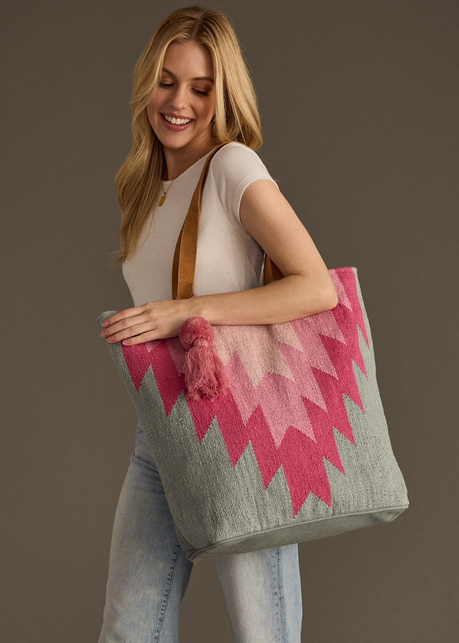 Woman holding a pink and gray patterned tote bag against a brown background