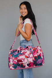 Woman holding a floral patterned handbag against a gray background