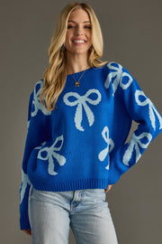 Woman wearing a blue sweater with white bow patterns against a gray background