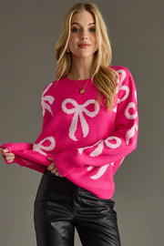 Woman wearing a pink sweater with white bow patterns against a gray background