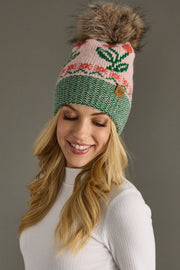 Woman wearing a colorful knit beanie with a fluffy pom-pom on a gray background