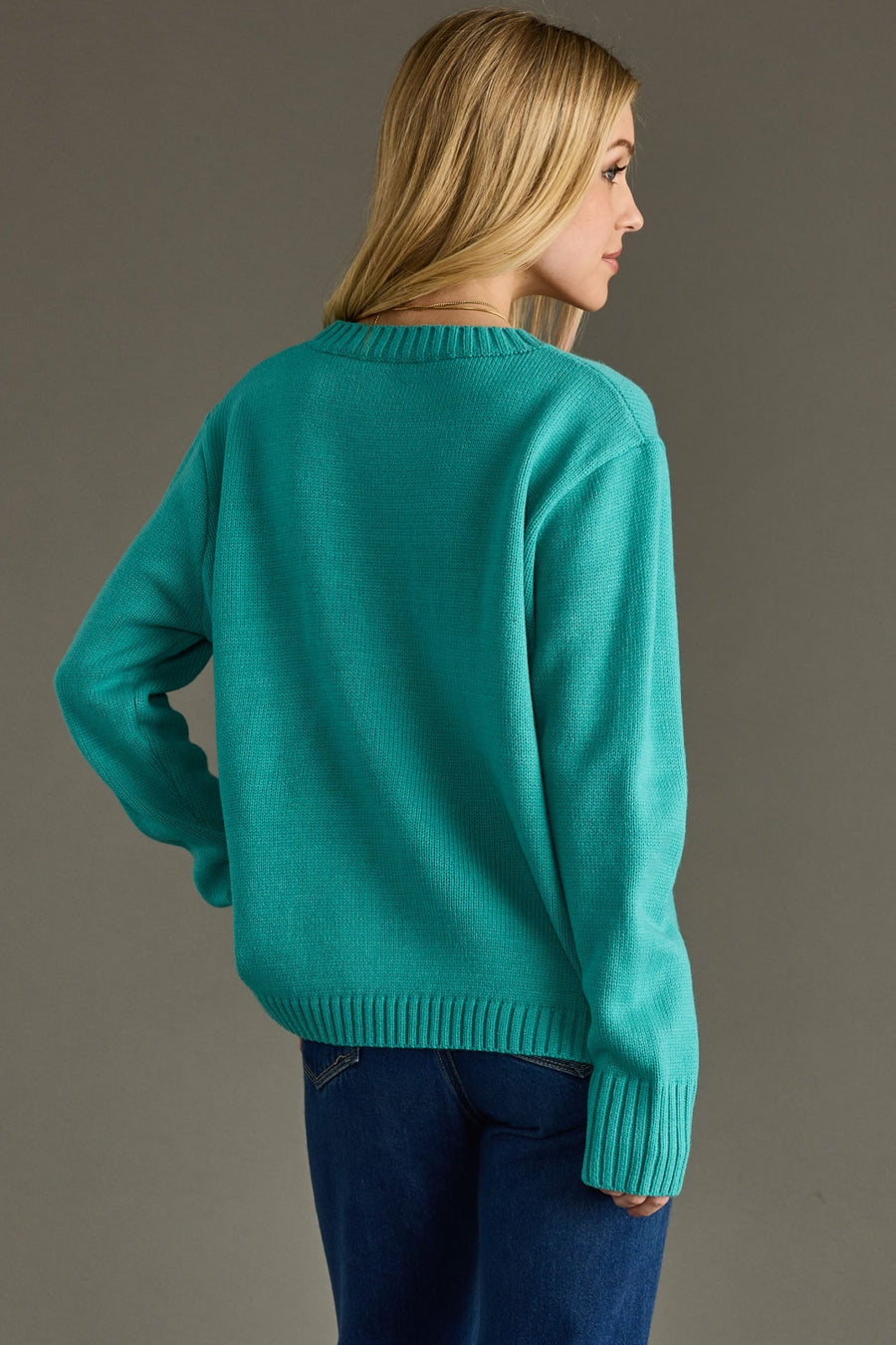 Woman wearing a teal sweater against a gray background