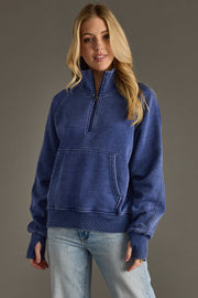 A woman with long blonde hair wears the Panache Apparel Collection Ryleigh Sweatshirt in navy, paired with light blue jeans, standing against a plain gray background.