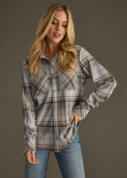 A woman with long blonde hair wears the Ozzy Super Soft Button Up by panacheaccessories in gray plaid, paired with blue jeans, standing against a plain gray background with one hand on her hip.