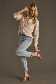 A woman wears the Blaire Super Soft Button Up by panacheaccessories with ripped cuffed jeans, balancing on one leg as she adjusts her heeled sandal, posing gracefully against a plain, neutral background.