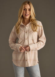 A woman with long blonde hair wears the panacheaccessories Blaire Super Soft Button Up and light blue jeans, standing against a dark background and smiling slightly at the camera.