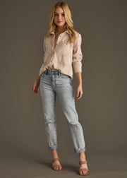 A woman with loose, wavy blonde hair wears the Blaire Super Soft Button Up by panacheaccessories, partially unbuttoned with rolled sleeves, paired with distressed cuffed jeans and strappy heeled sandals against a plain background.