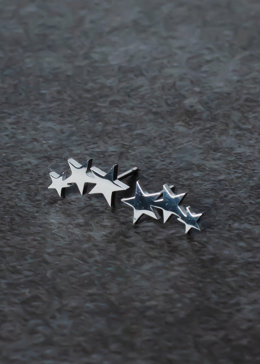 The Lexi Star Stud Earrings – Silver by panacheaccessories are lead and nickel free, featuring a stylish triple star design, each shaped like a row of five stars and shown on a textured dark gray surface.