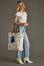 Woman holding a tote bag with a pattern of people skiing against a gray background