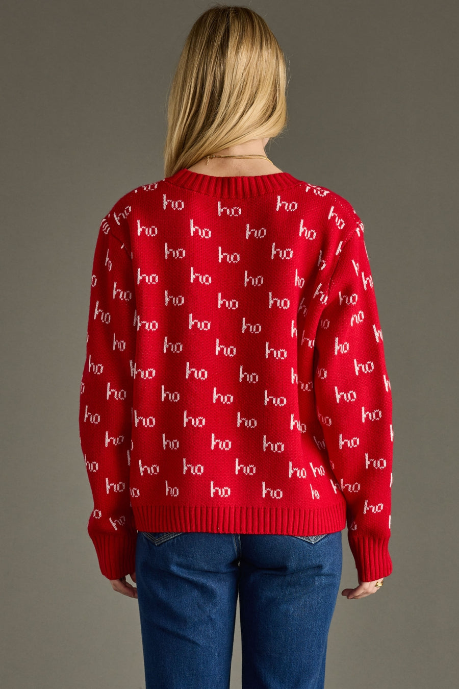 Person wearing a red sweater with 'ho ho ho' pattern on a gray background