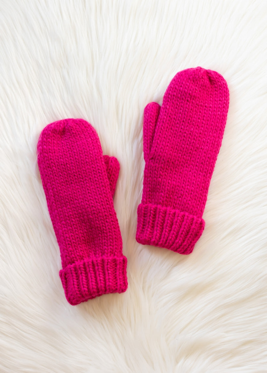 Pair of bright pink mittens on a white fur surface