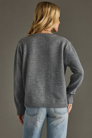 Person wearing a gray sweater and blue jeans against a gray background