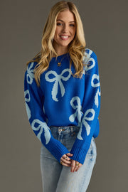 Woman wearing a blue sweater with white bow patterns against a gray background