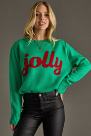 Woman wearing a green sweater with red text 'jolly' against a gray background