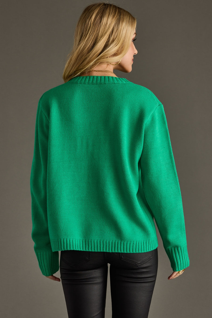 Person wearing a green sweater against a gray background