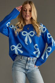 Woman wearing a blue sweater with white bow patterns against a gray background
