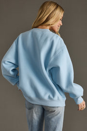 Person wearing a light blue sweatshirt and jeans against a plain background