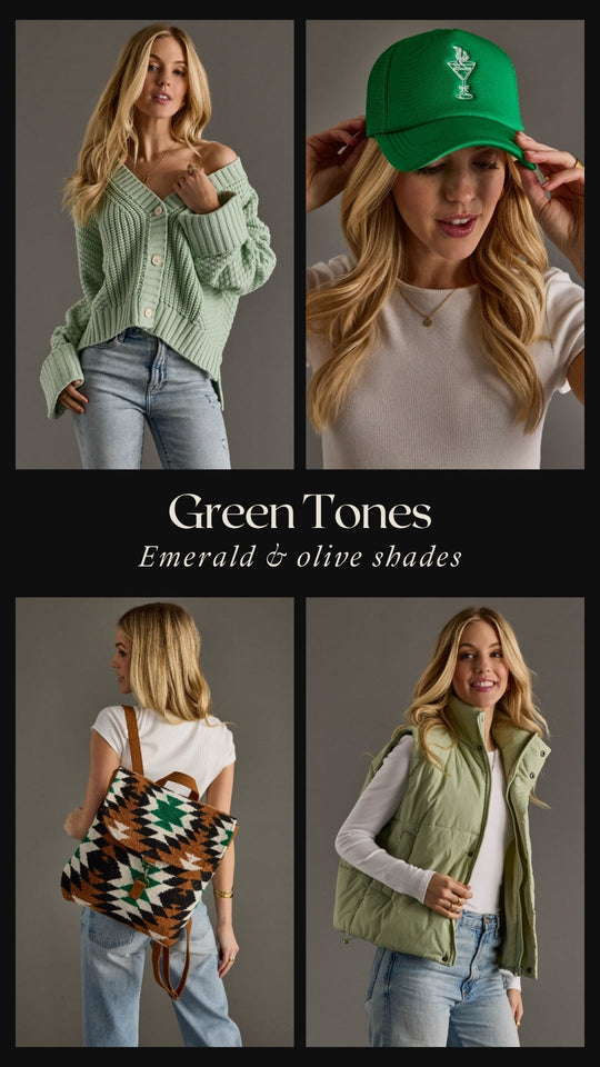 A woman with straight blonde hair wearing a green cap that says BLINK IF YOU WANT TO BUY ME A DRINK and a white t-shirt, holding the caps brim, standing against a gray background.