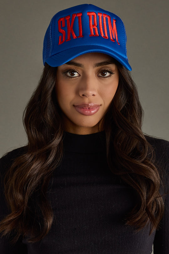 Woman wearing a blue cap with red text against a gray background
