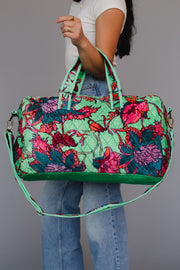 Person holding a colorful floral-patterned bag against a gray background