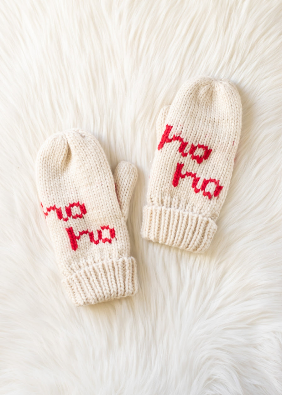 Pair of cream-colored mittens with 'ho ho' text on a white fur background