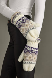 Pair of knit mittens with a pattern worn by a person against a neutral background
