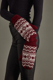 Person wearing red and white patterned mittens on a gray background