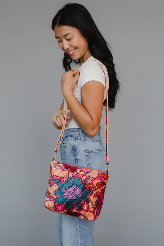 Woman holding a colorful floral-patterned bag against a gray background