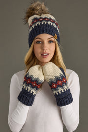 Woman wearing a knit hat and mittens with a pattern on a gray background