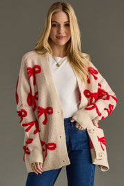Woman wearing a beige cardigan with red bow patterns on a gray background