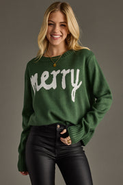 Woman wearing a green sweater with 'merry' text on a gray background