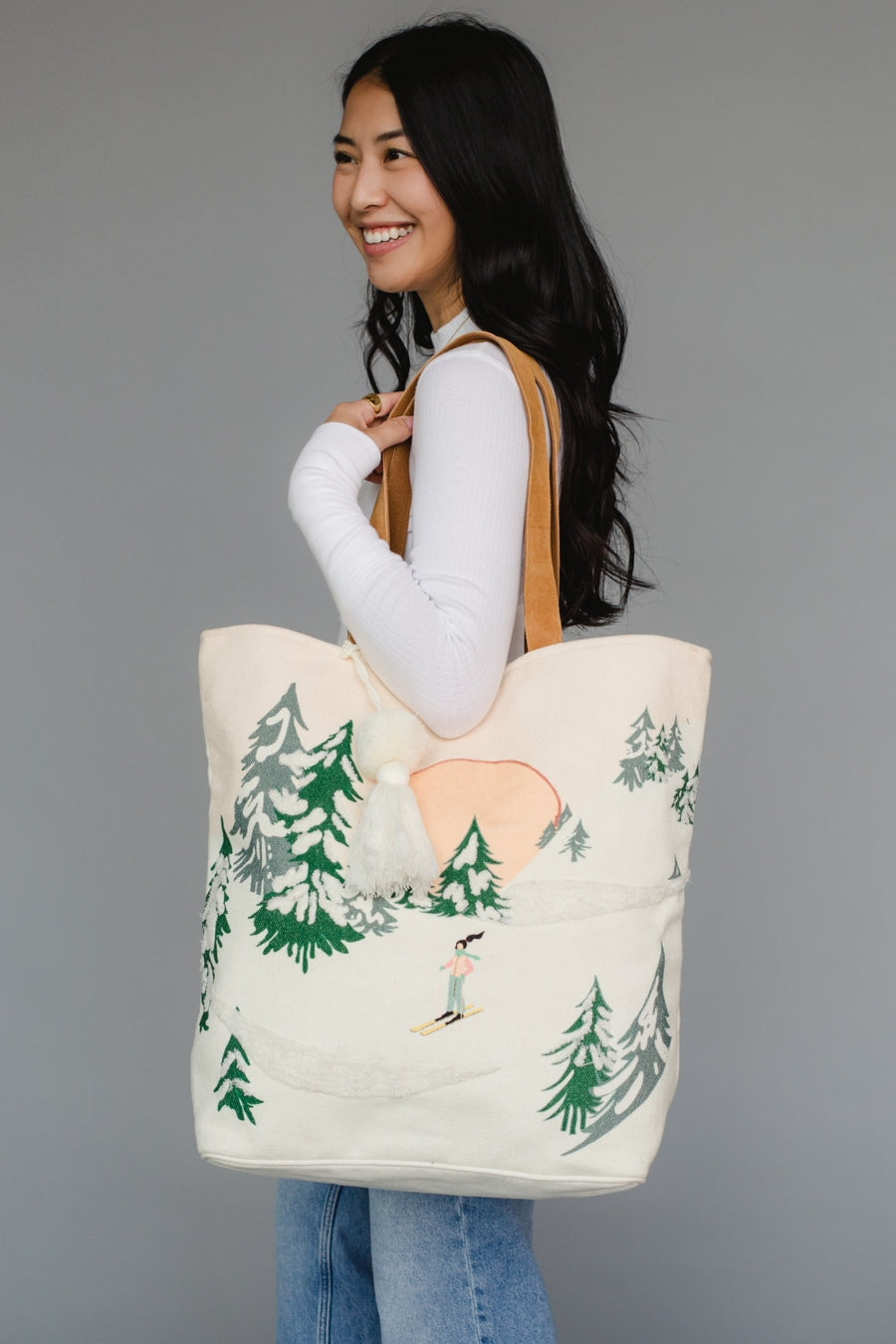 Woman holding a tote bag with a nature design against a gray background