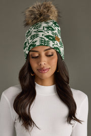 Woman wearing a green and white patterned beanie with a pom-pom on a gray background