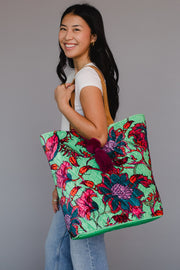 Woman holding a colorful floral tote bag against a plain background