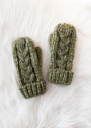 Pair of green knit mittens on a white fur surface