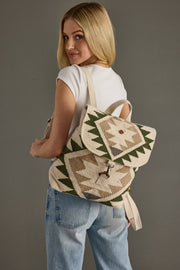 Woman wearing a patterned backpack against a gray background