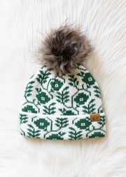 Green patterned beanie with fur pom-pom on a white background