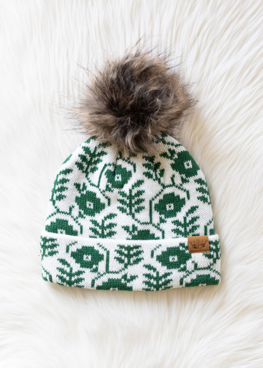 Green patterned beanie with fur pom-pom on a white background