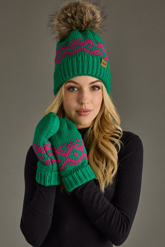 Person wearing a green knit hat and mittens with pink patterns on a gray background