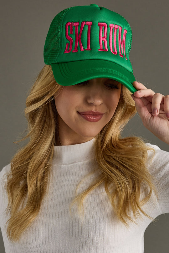 Person wearing a green cap with pink text on a gray background