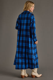 Woman wearing a long blue plaid coat against a gray background