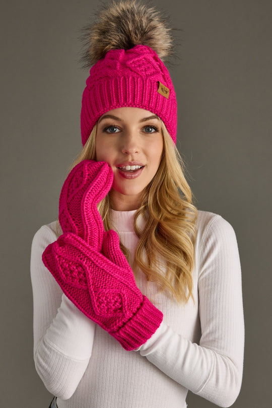 Woman wearing a bright pink knit hat and gloves on a gray background